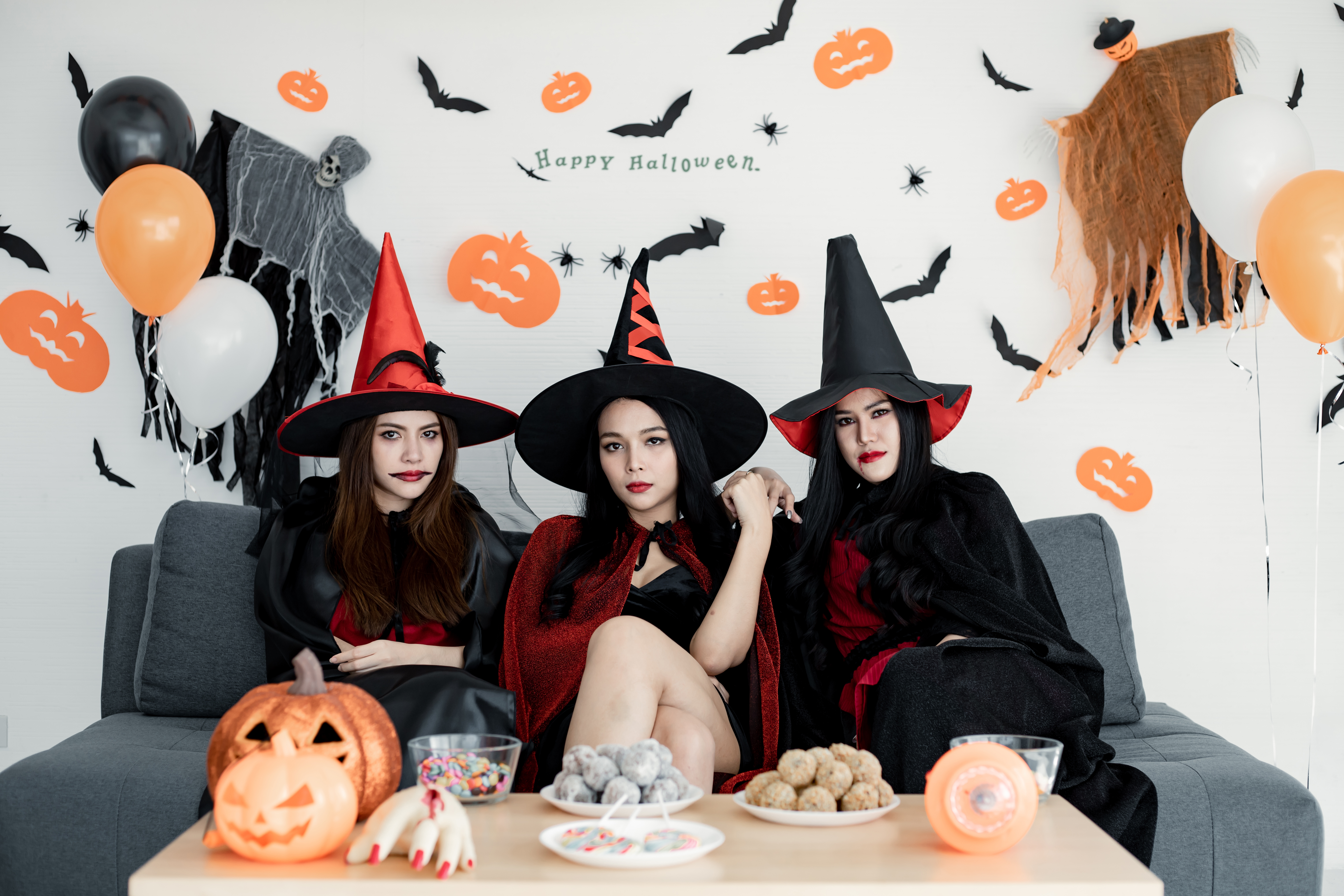 Three girls dressed as witches celebrating at a Halloween party.