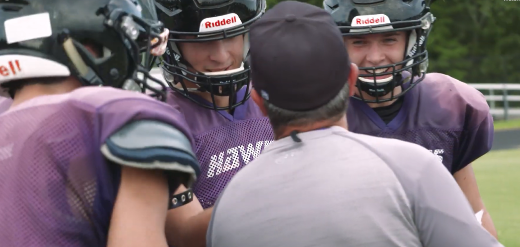 Football players talk with their coach about underage drinking.