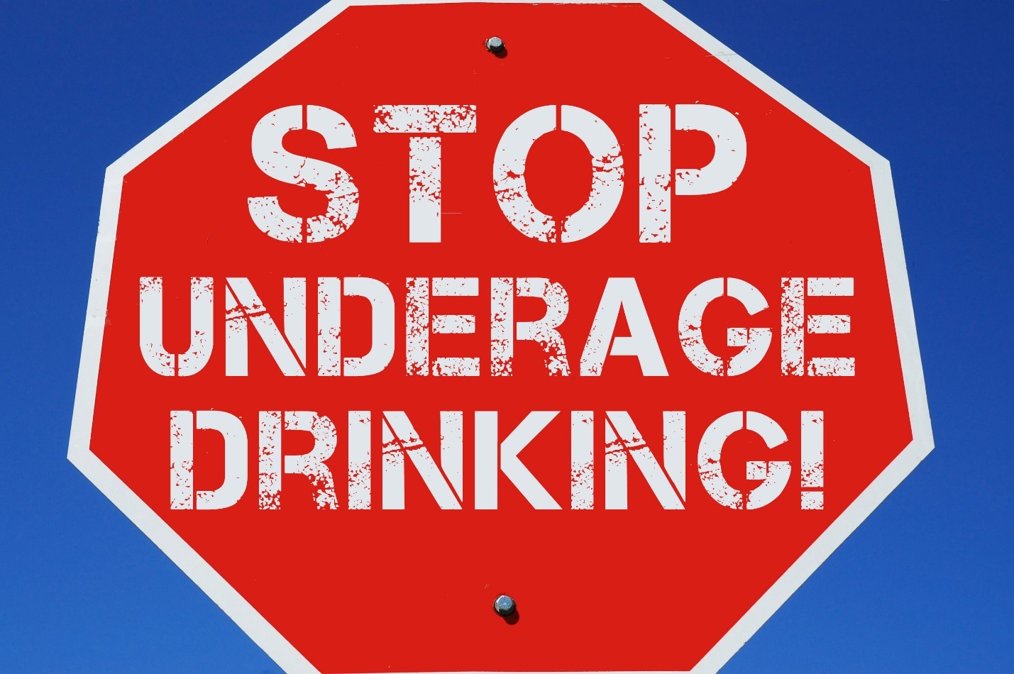 A large red stop sign telling people to stop underage drinking.