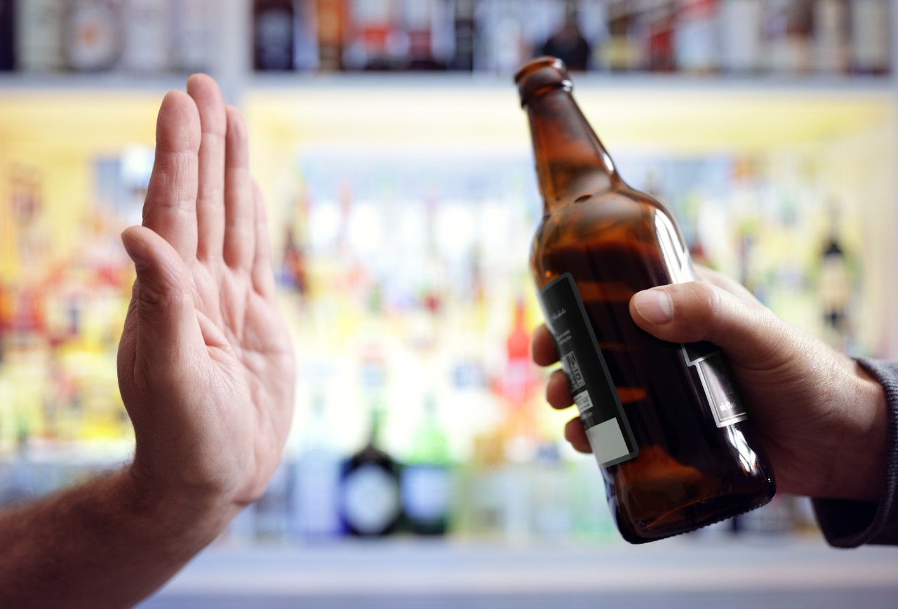 A teenager holding up their hand to say "no" to being offered an alcoholic beverage.