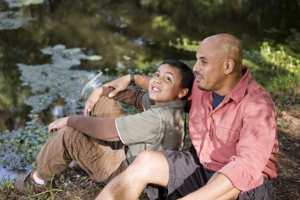 Latinx father told to his son by a pond.