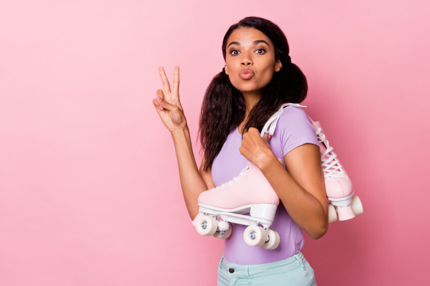 Young teen girl with roller skates holding up the peace sign